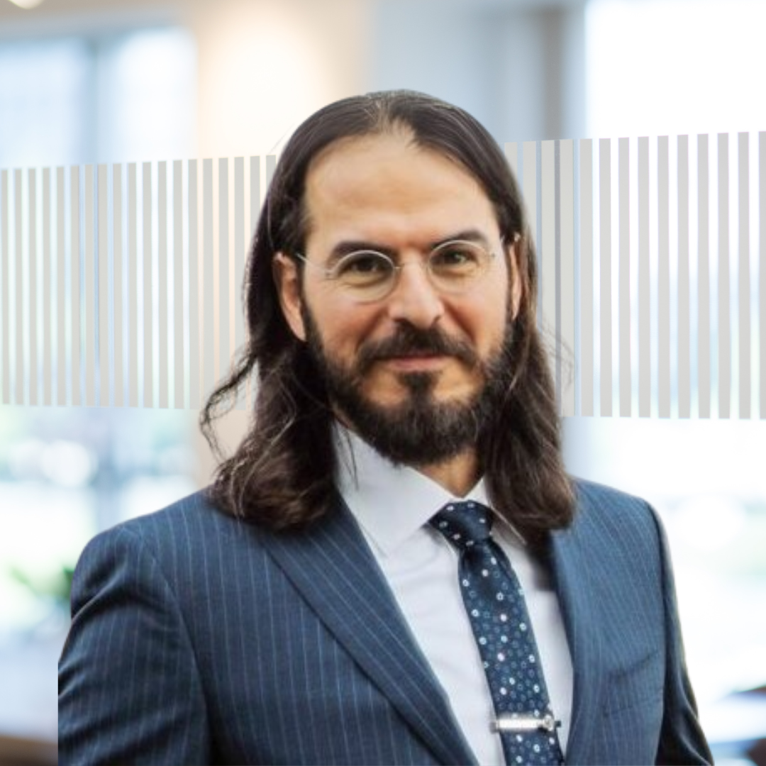 Headshot of Dr. Keiwan Wind, a smiling man with long dark hair, a beard, and glasses, wearing a suit and tie.