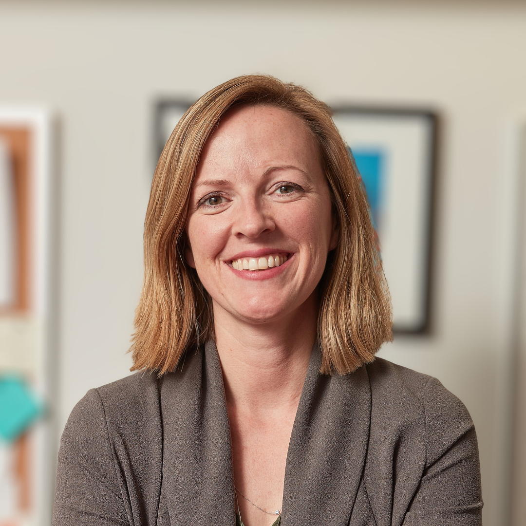 Headshot of Erin Reid, a smiling woman light brown hair and a gray jacket.